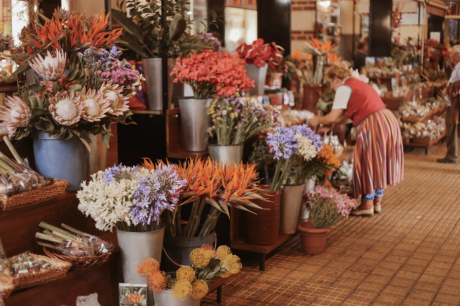 Flower section in Mercado Dos Lavradores. Take a look on the colorful uniform of the saleswoman